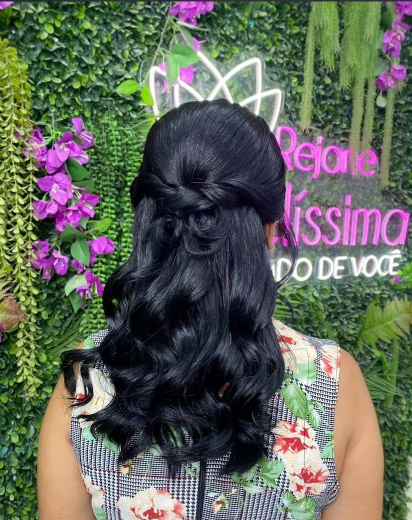 Penteado semipreso com ondas em cabelo preto, diante do painel verde e do letreiro luminoso do salão
